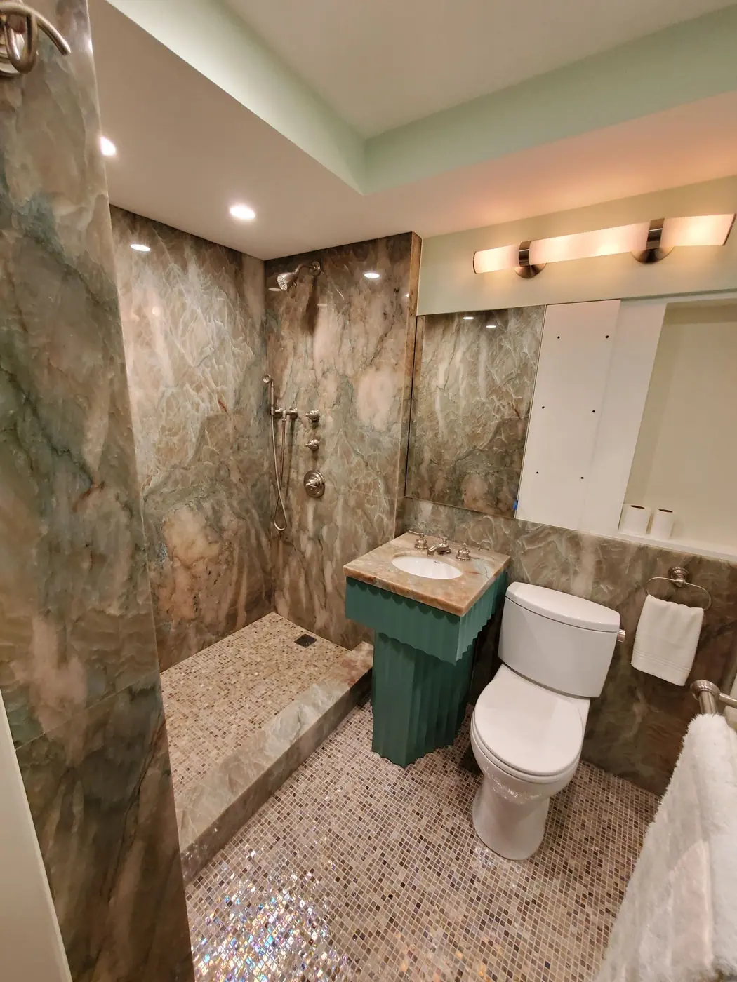 Finished bathroom clad in book matched marble with a stone vanity