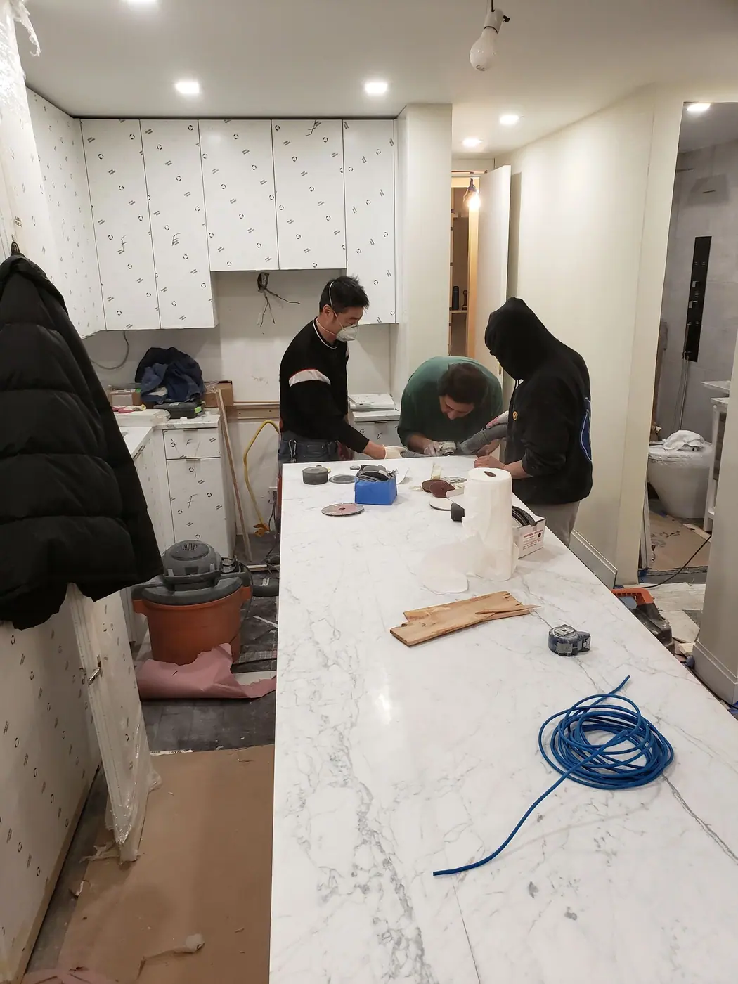 Crew setting the stone waterfall counter on the kitchen island of the Sutton Place condo